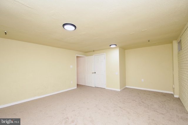 unfurnished bedroom featuring a textured ceiling, a closet, and light colored carpet