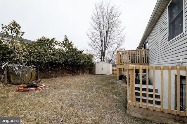 view of yard featuring an outbuilding, a fenced backyard, a fire pit, a storage shed, and a wooden deck