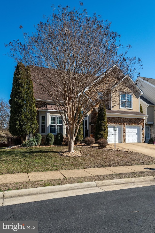 view of front of house with a garage, concrete driveway, stone siding, stucco siding, and a front yard