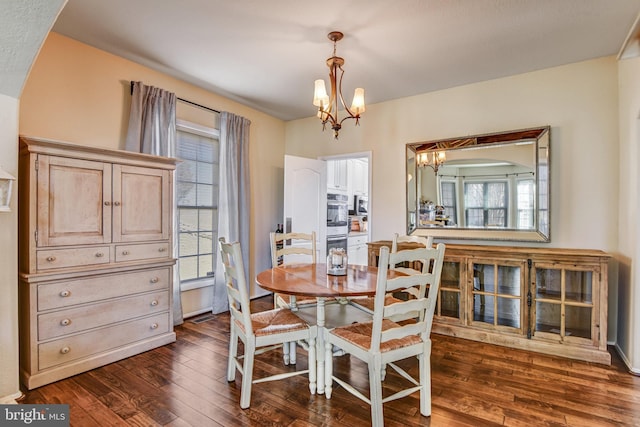 dining room featuring dark wood-style floors, arched walkways, and a notable chandelier