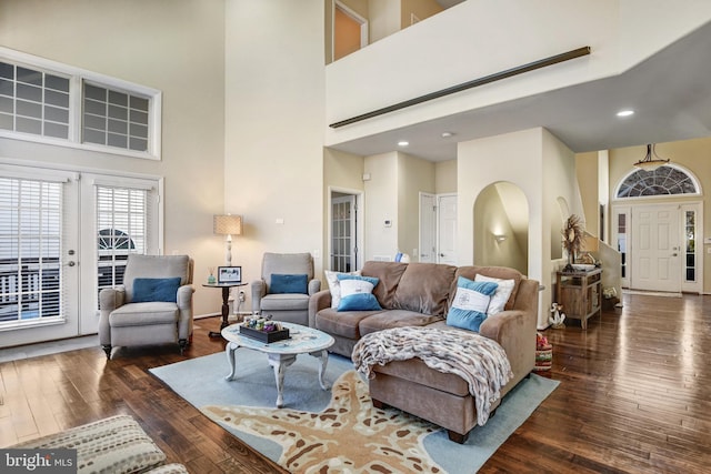 living area with arched walkways, dark wood finished floors, a high ceiling, french doors, and recessed lighting