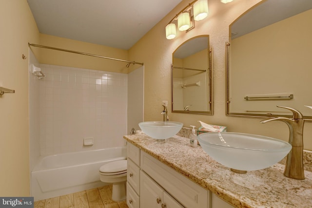 bathroom featuring double vanity, bathing tub / shower combination, a sink, and wood finished floors