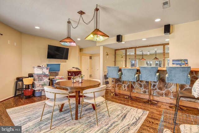 dining space featuring a dry bar, wood finished floors, visible vents, and recessed lighting