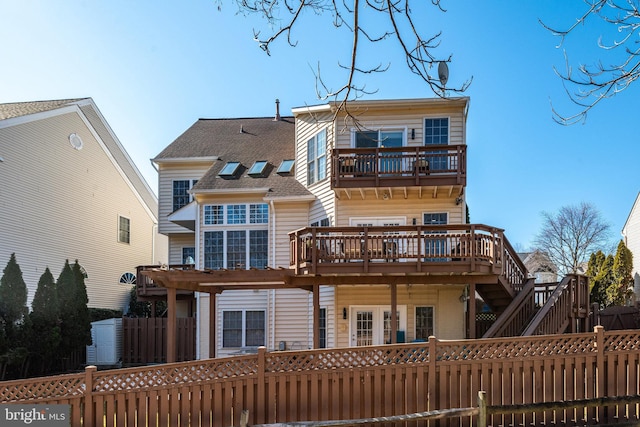 rear view of property featuring a deck, a fenced front yard, a balcony, and a pergola