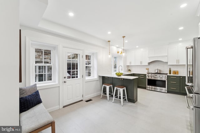 kitchen featuring pendant lighting, white cabinetry, a kitchen breakfast bar, premium appliances, and kitchen peninsula