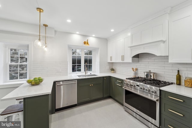 kitchen with appliances with stainless steel finishes, decorative light fixtures, white cabinetry, sink, and kitchen peninsula