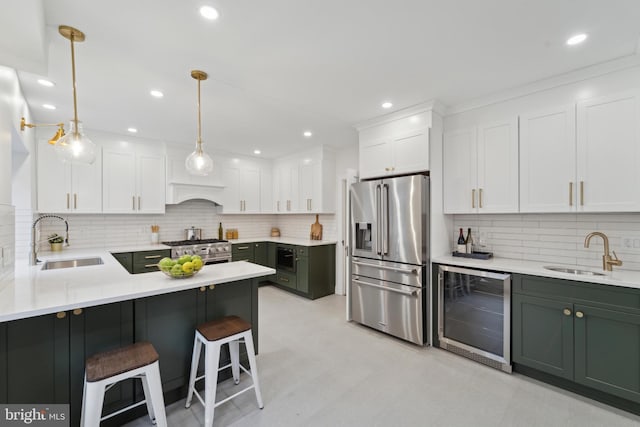 kitchen with high quality appliances, sink, white cabinets, beverage cooler, and hanging light fixtures