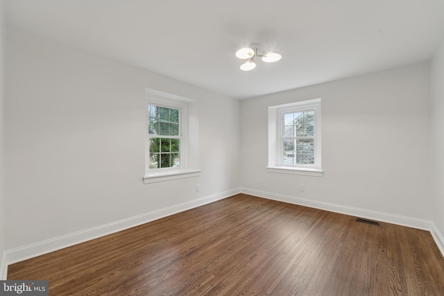 empty room featuring plenty of natural light and dark hardwood / wood-style flooring