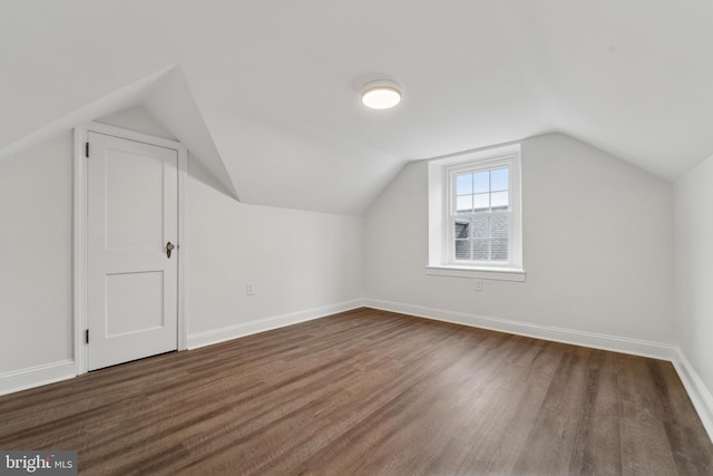 additional living space featuring vaulted ceiling and dark hardwood / wood-style flooring