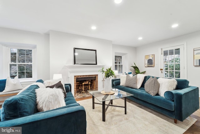 living room with a brick fireplace and light wood-type flooring