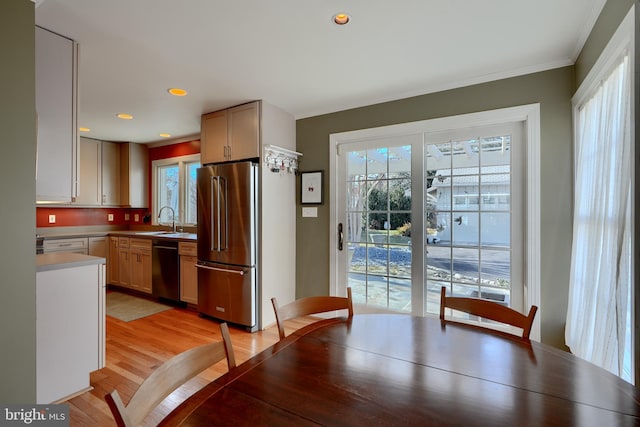 interior space with high end refrigerator, a sink, black dishwasher, light countertops, and light brown cabinetry