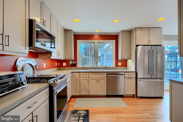 kitchen with stainless steel appliances, light countertops, a sink, and light wood-style flooring