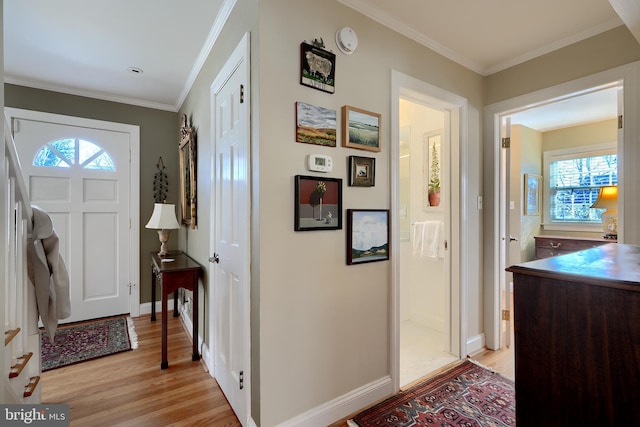 foyer entrance featuring light wood finished floors, baseboards, and crown molding