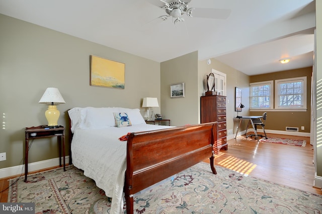 bedroom with a ceiling fan, wood finished floors, visible vents, and baseboards