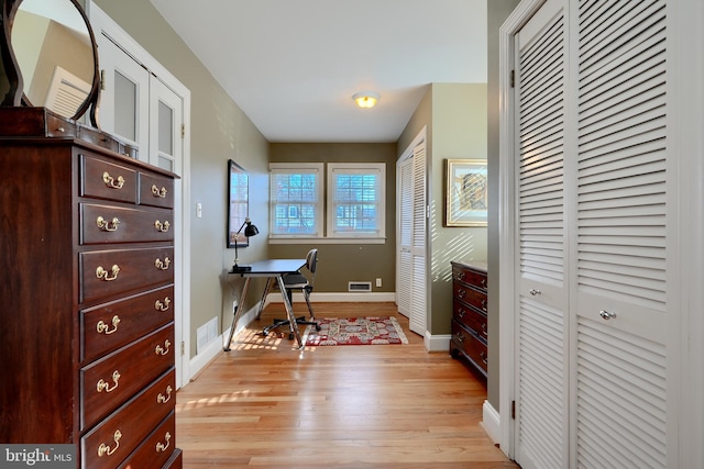 office space featuring light wood-type flooring, visible vents, and baseboards