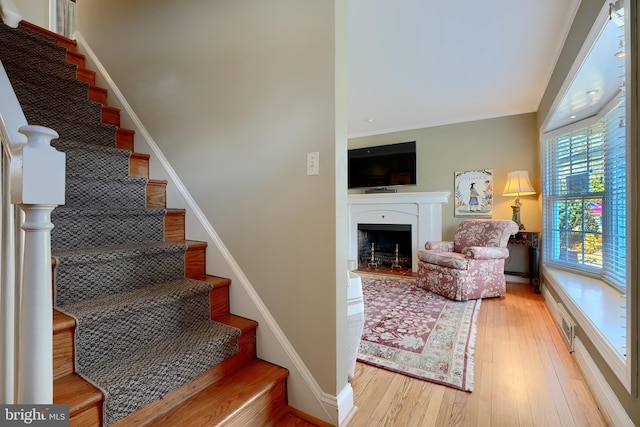 staircase featuring a fireplace, wood finished floors, and baseboards