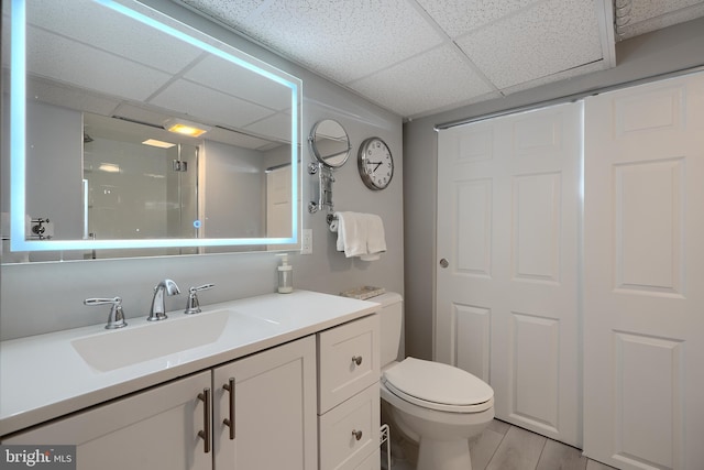 full bath with toilet, wood finished floors, a drop ceiling, and vanity