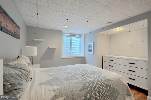 bedroom featuring a drop ceiling and wood finished floors