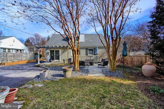 rear view of house with brick siding, fence, a yard, roof with shingles, and a patio area