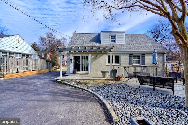 back of property with a patio, brick siding, a shingled roof, and fence