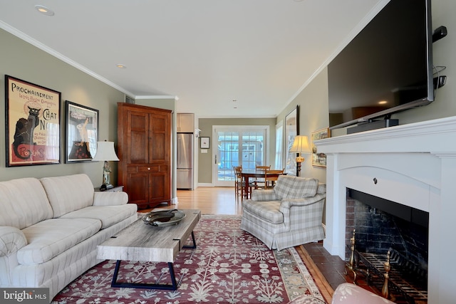 living room with a fireplace with flush hearth, crown molding, and wood finished floors