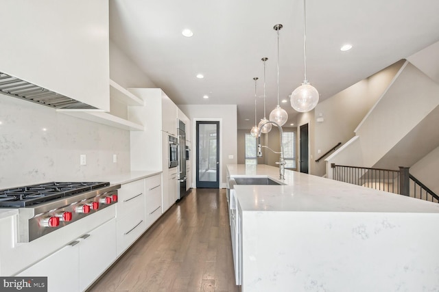 kitchen with a large island, sink, dark hardwood / wood-style flooring, decorative light fixtures, and stainless steel gas stovetop