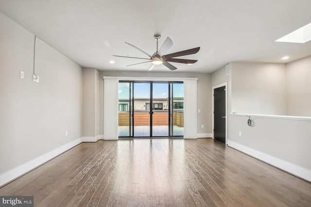 unfurnished room featuring ceiling fan, a skylight, and hardwood / wood-style floors