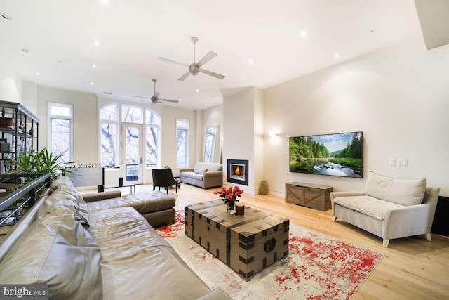 living area with light wood-type flooring, recessed lighting, baseboards, and a glass covered fireplace