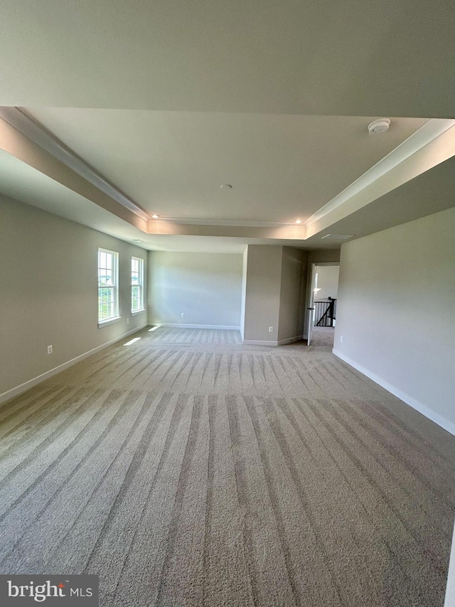 carpeted empty room featuring a tray ceiling