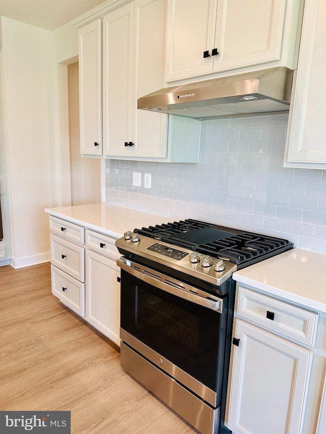 kitchen featuring white cabinetry, stainless steel range with gas cooktop, tasteful backsplash, and light wood-type flooring