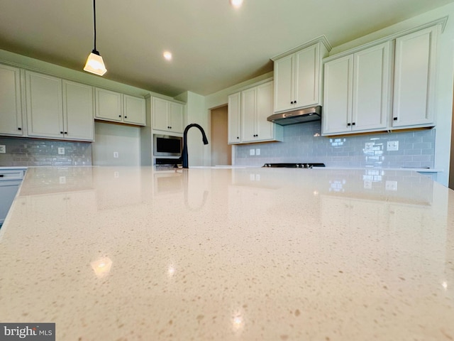 kitchen featuring pendant lighting, light stone countertops, and backsplash