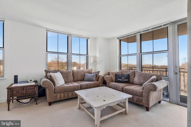 living room with a textured ceiling, expansive windows, and light carpet