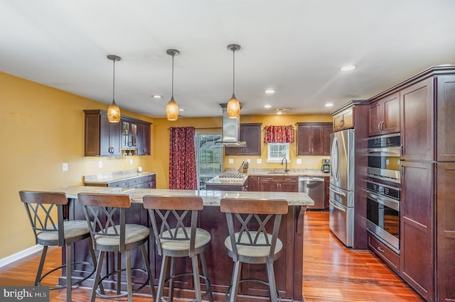 kitchen featuring sink, a center island, light wood-type flooring, pendant lighting, and stainless steel appliances