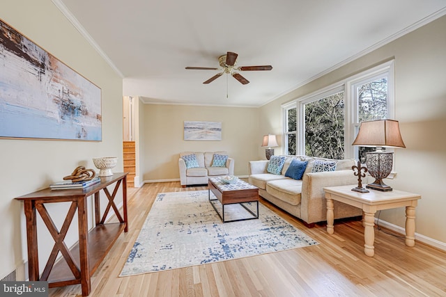 living room featuring baseboards, ornamental molding, a ceiling fan, and light wood-style floors