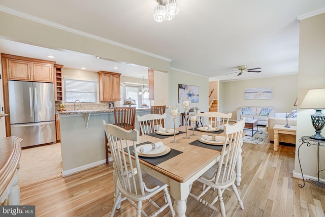 dining area with light wood finished floors, ornamental molding, and a ceiling fan