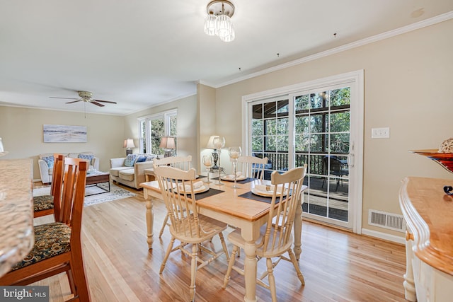 dining space featuring visible vents, light wood-style flooring, ornamental molding, ceiling fan, and baseboards