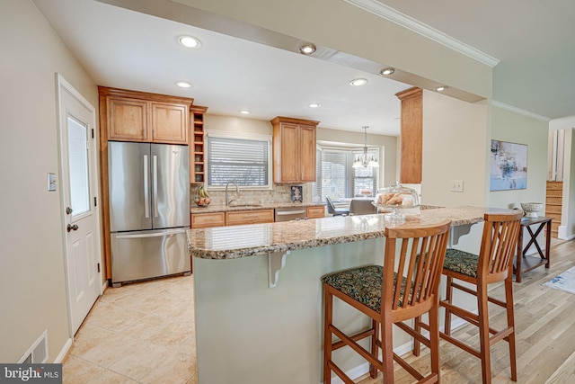 kitchen with tasteful backsplash, ornamental molding, a kitchen breakfast bar, a peninsula, and stainless steel appliances