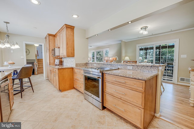 kitchen featuring light stone counters, visible vents, appliances with stainless steel finishes, a peninsula, and a kitchen breakfast bar