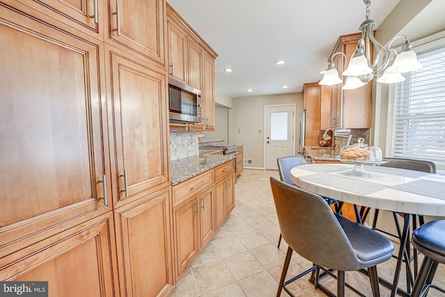 kitchen featuring appliances with stainless steel finishes, pendant lighting, plenty of natural light, and light stone countertops