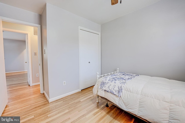 bedroom with a closet, baseboards, and light wood finished floors