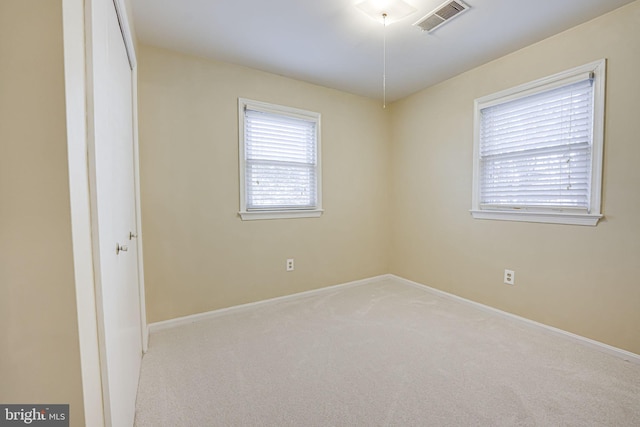 empty room featuring light carpet, visible vents, and baseboards