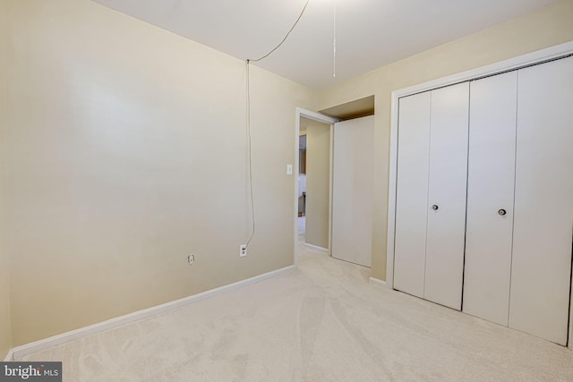 unfurnished bedroom featuring a closet, light carpet, and baseboards