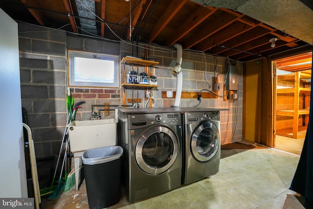 laundry room featuring laundry area, washing machine and dryer, electric panel, and a sink