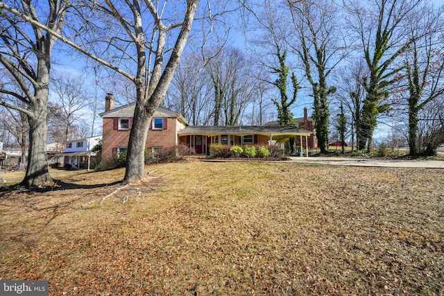 view of front facade featuring a porch, a chimney, a front lawn, and brick siding