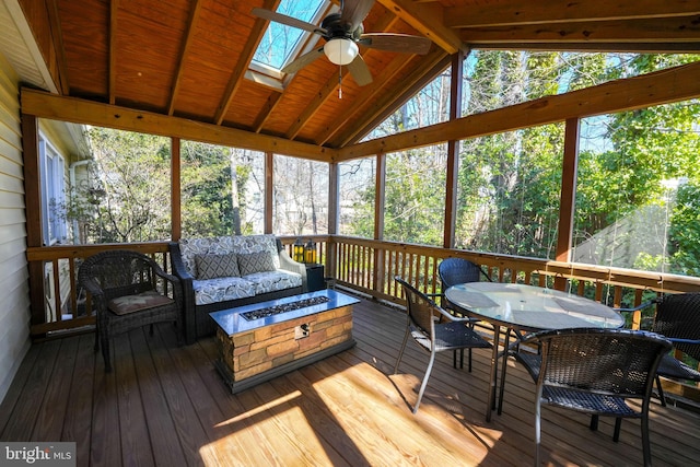 sunroom featuring a ceiling fan, a wealth of natural light, and lofted ceiling with skylight