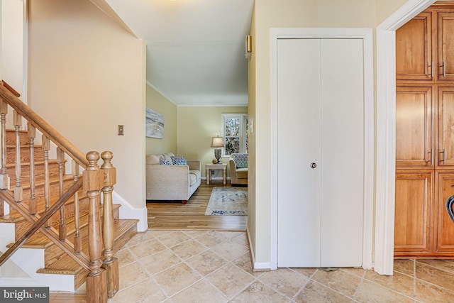 foyer with ornamental molding, stairway, and baseboards