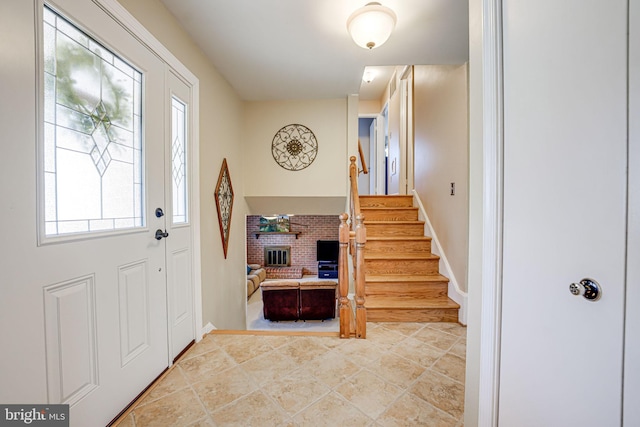 entrance foyer with a fireplace, stairway, and baseboards