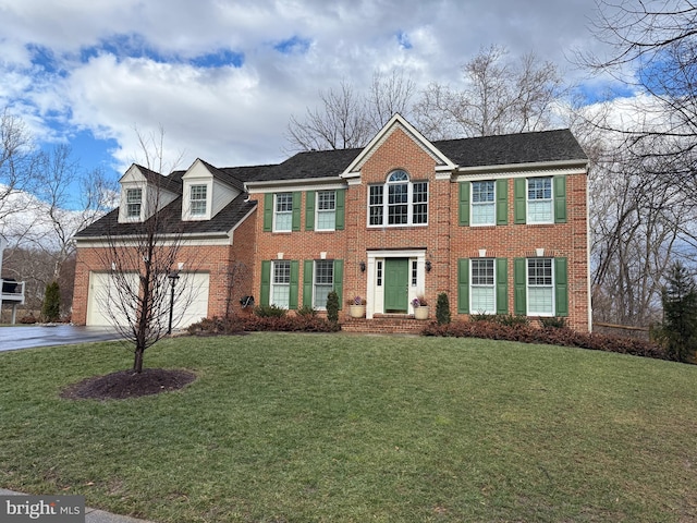 colonial inspired home with driveway, brick siding, a front lawn, and an attached garage