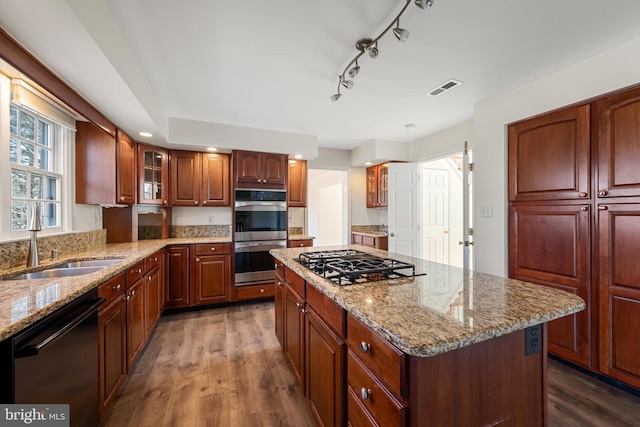 kitchen featuring visible vents, glass insert cabinets, appliances with stainless steel finishes, dark wood-type flooring, and a center island