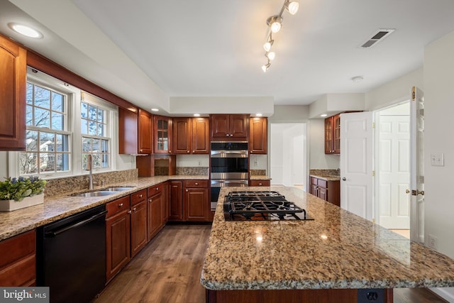 kitchen with visible vents, glass insert cabinets, a kitchen island, a sink, and black appliances